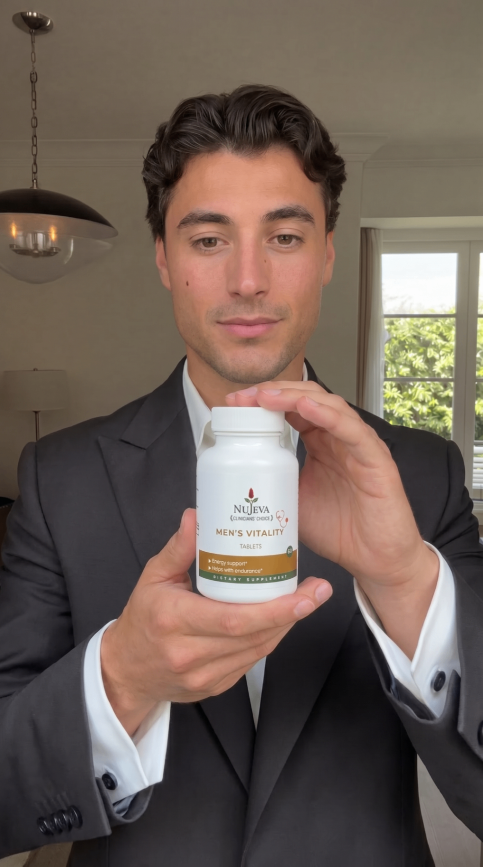 Man in suit holding Nūjeva Men's Vitality Tablets
